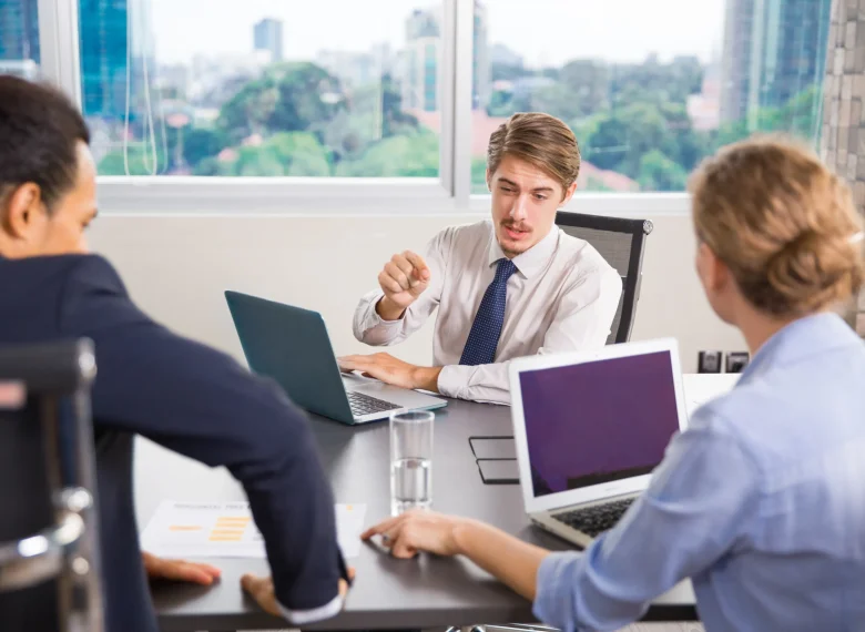 businessman-sitting-with-laptop-talking-other-colleagues