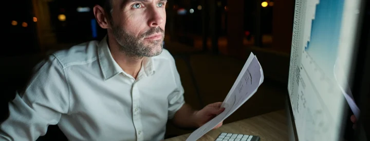 focused-man-with-document-using-computer